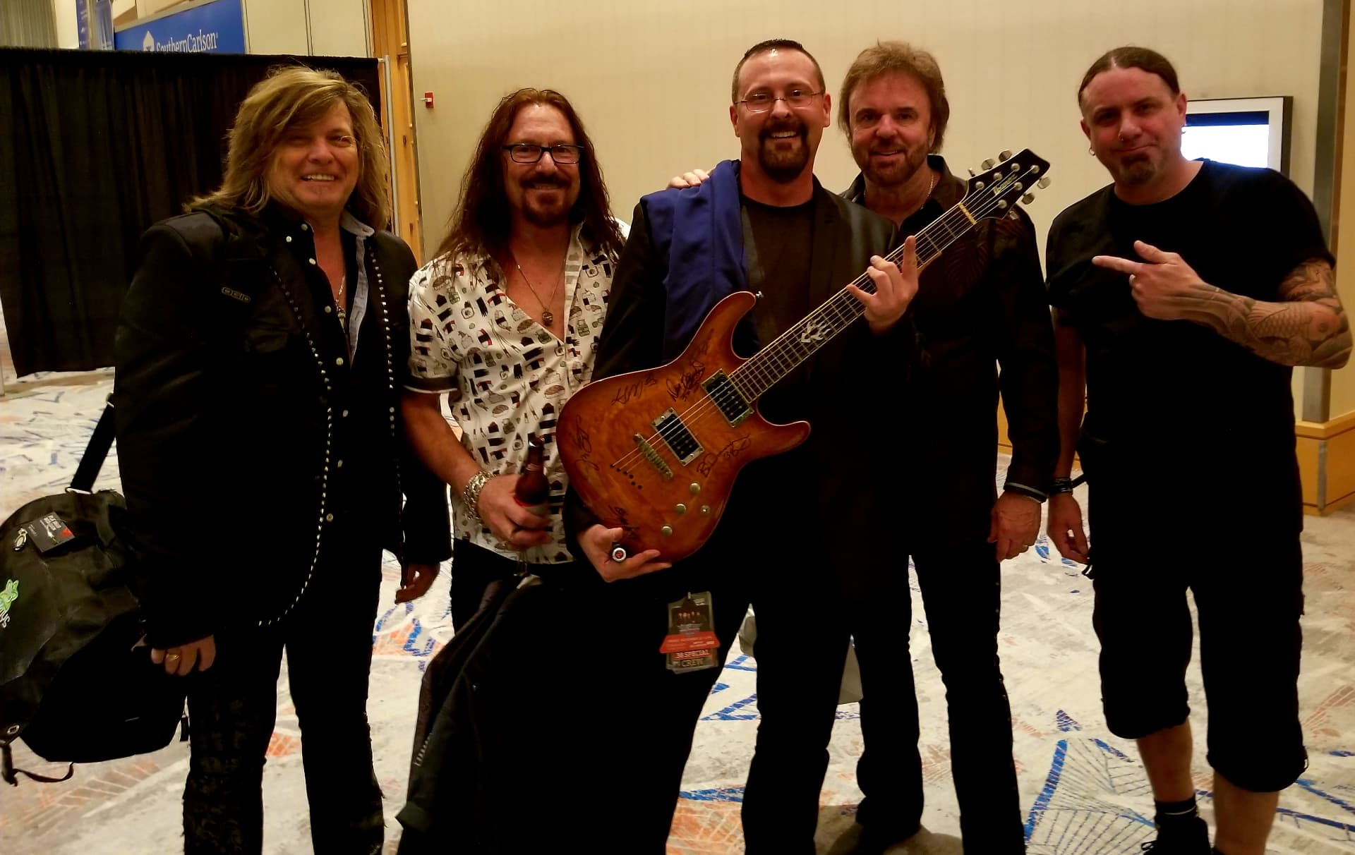 Barry Dunaway and bandmates with a signed guitar